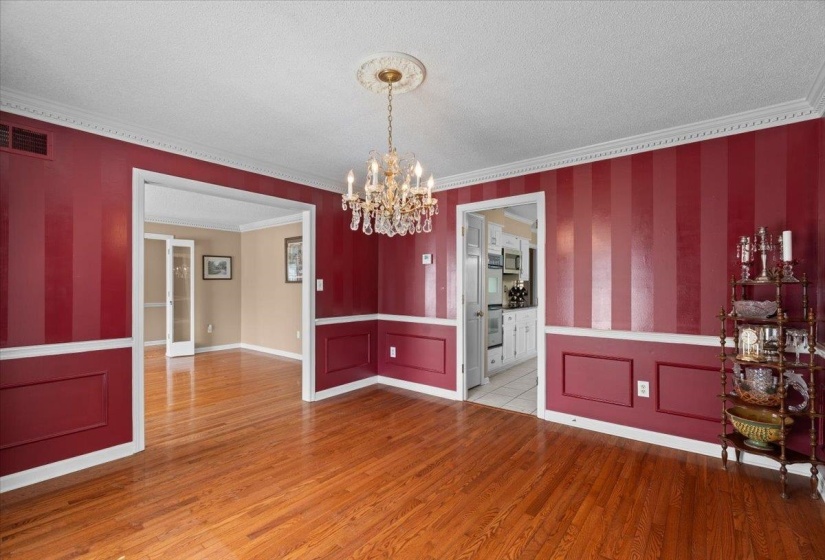 Unfurnished dining area with hanging lights, crown molding, a textured ceiling, light wood-style flooring, and wallpapered walls