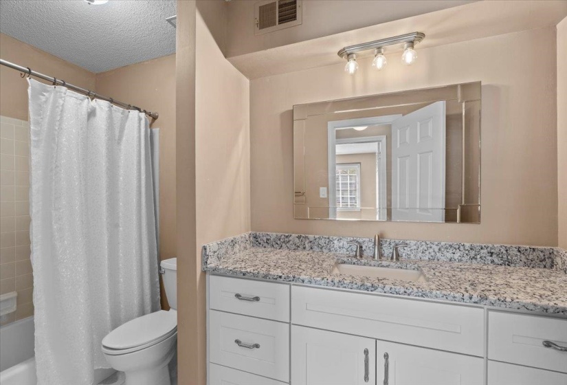 Full bath with vanity, shower / bathtub combination with curtain, and a textured ceiling