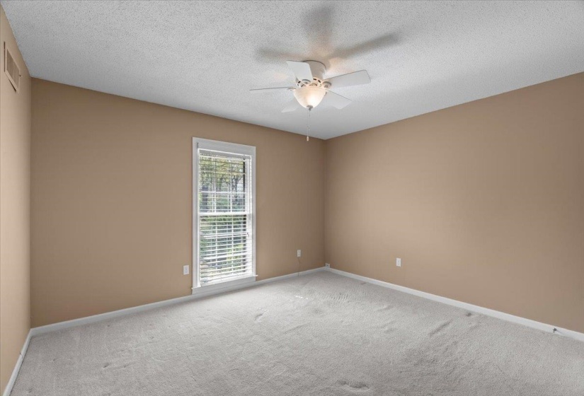 Spare room with a textured ceiling, a ceiling fan, and light carpet