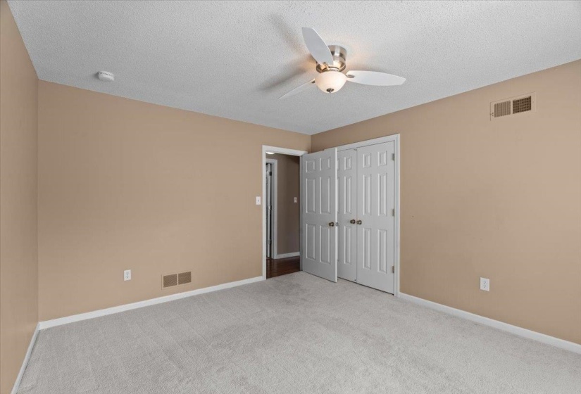 Unfurnished bedroom featuring light colored carpet, a ceiling fan, a textured ceiling, and a closet