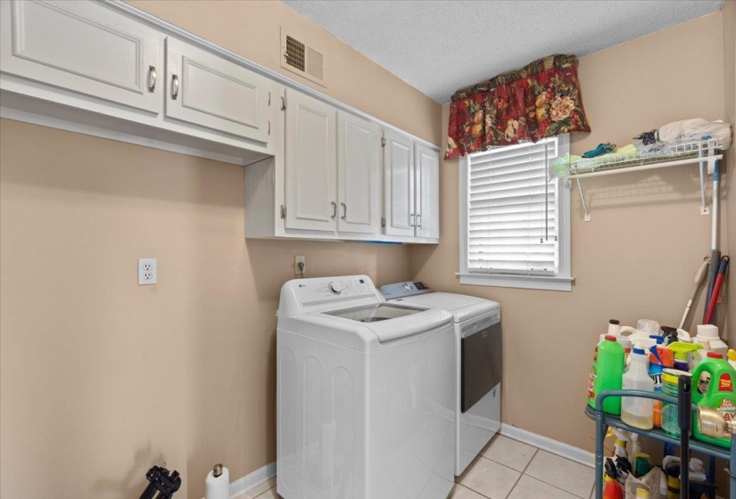 Laundry room featuring cabinet space, separate washer and dryer, a textured ceiling, and light tile patterned floors