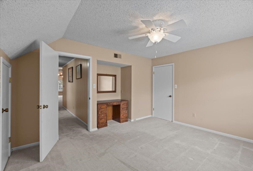 Unfurnished bedroom featuring a textured ceiling, ceiling fan, and light carpet