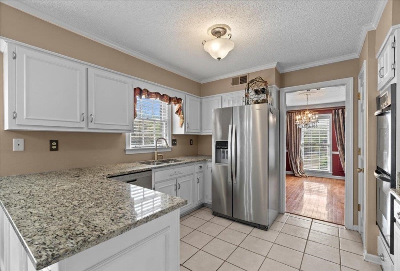 Kitchen featuring stainless steel appliances, light stone counters, white cabinetry, a textured ceiling, and a peninsula