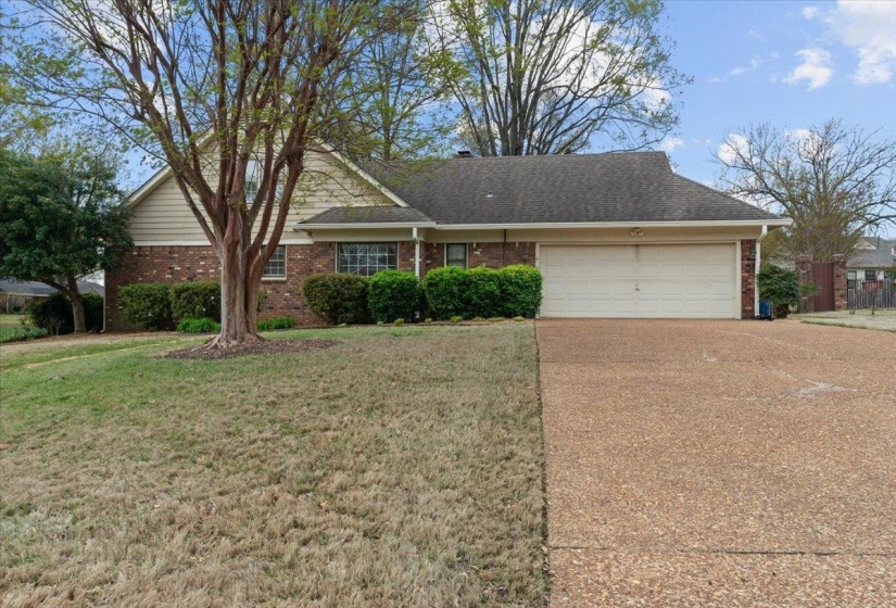 View of front of property featuring a garage, brick siding, driveway, and a front yard