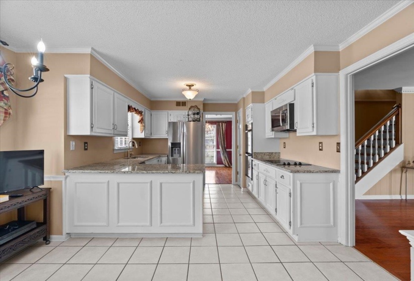 Kitchen featuring light stone counters, a textured ceiling, a peninsula, stainless steel appliances, and white cabinets