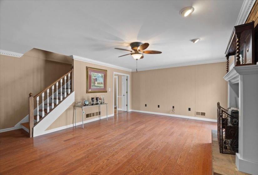 Unfurnished living room with a ceiling fan, light wood finished floors, ornamental molding, and a fireplace