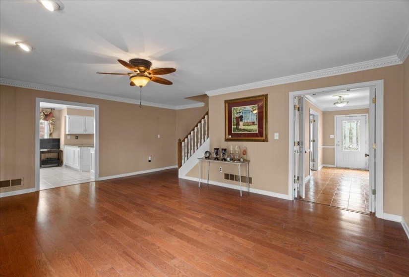 Unfurnished living room with a ceiling fan, light wood-style flooring, and crown molding