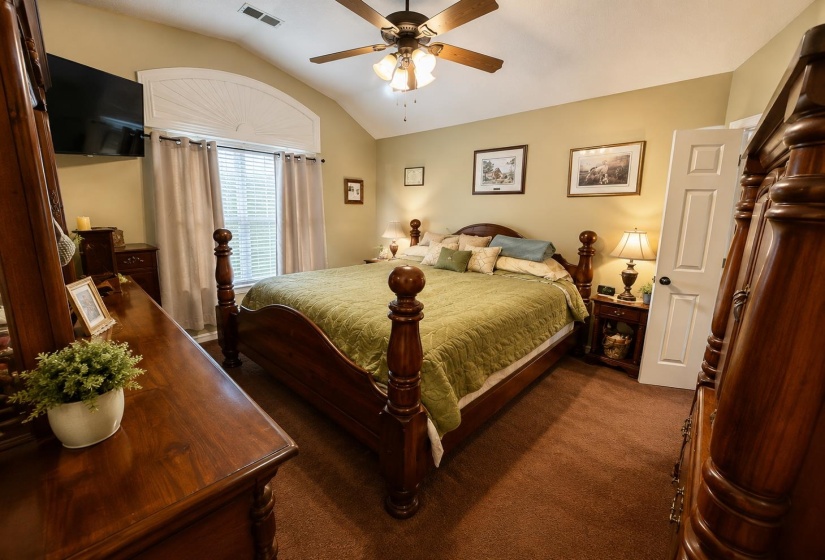 Vaulted ceiling room featuring a ceiling fan with integrated lighting, arched window with decorative half-round accent, and light-toned walls