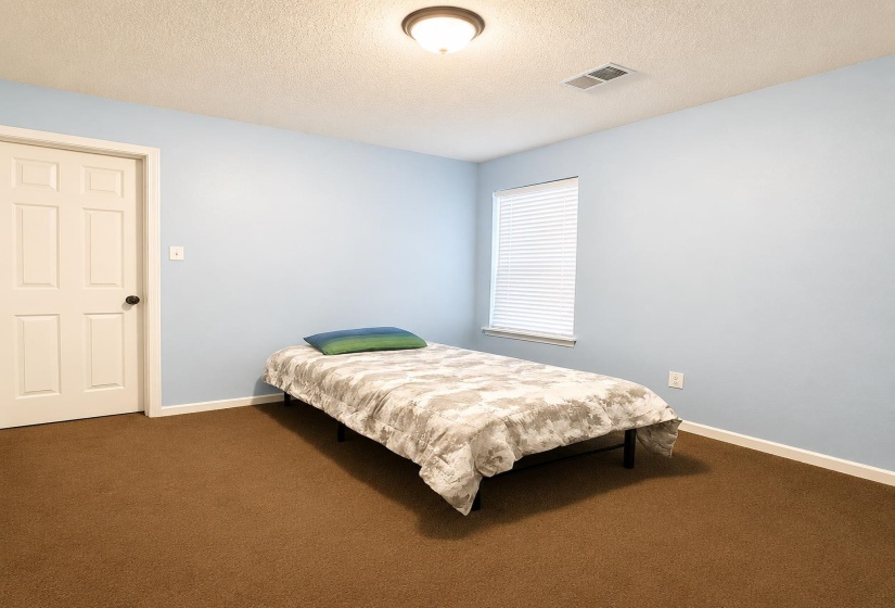 Room featuring light blue walls, brown carpet, a single window with blinds, and a paneled white door