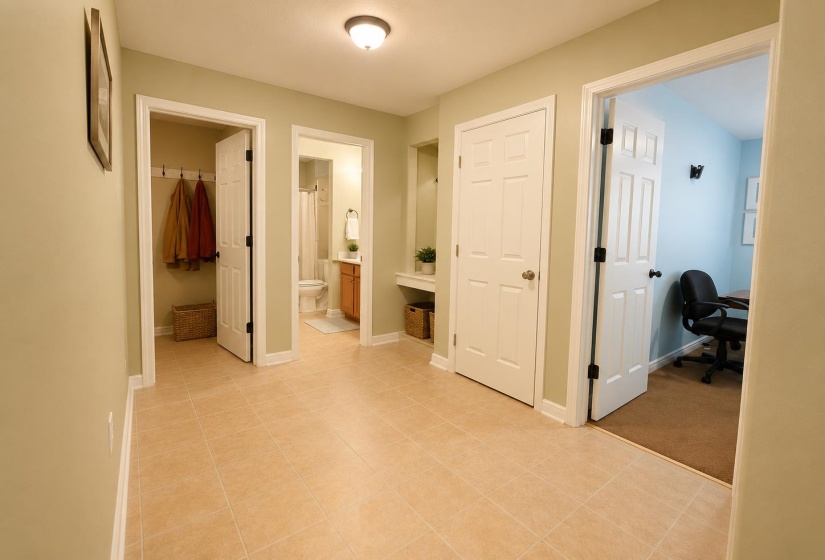 Neutral-toned tile flooring extends through this interior hallway, featuring white trim and doors