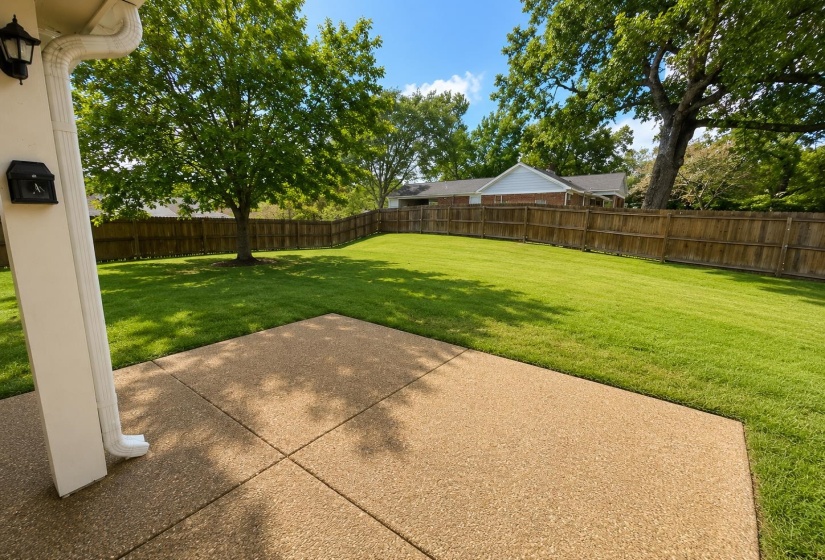 Expansive backyard featuring a large grass lawn, mature trees, and a full privacy fence