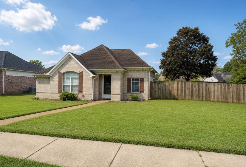 Traditional style residence featuring a light brick exterior, a dark shingle roof, and brown decorative window shutters