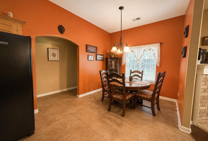 Dining area featuring tile flooring, an arched entryway, and a window with blinds