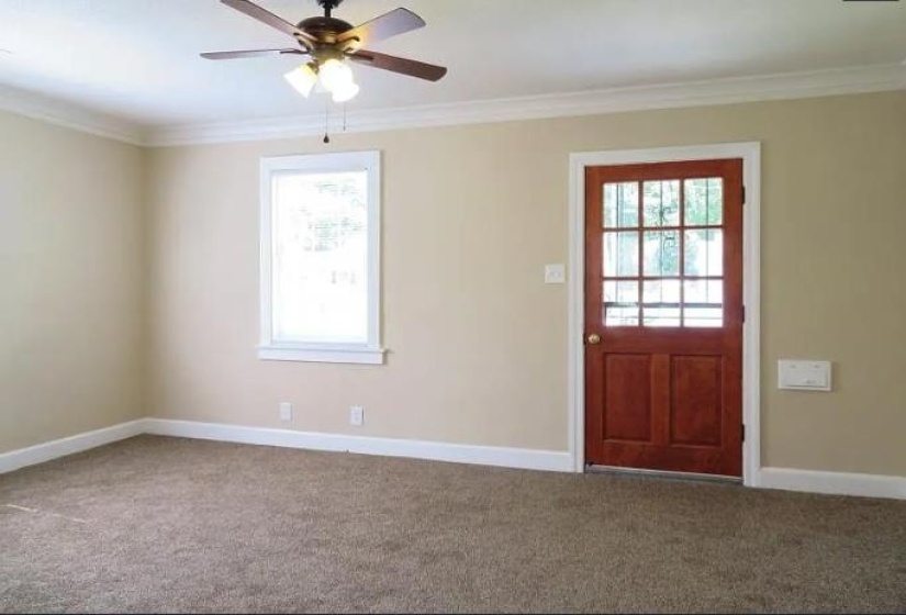 Carpeted foyer with ceiling fan and ornamental molding