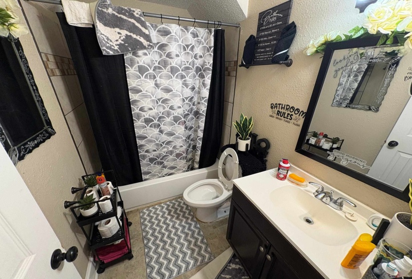 Full bathroom featuring a single vanity, a framed wall mirror, a toilet, and a shower-over-tub combination