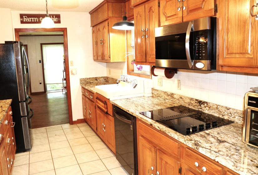 Kitchen featuring solid wood cabinetry, granite-finish countertops, and white tile flooring