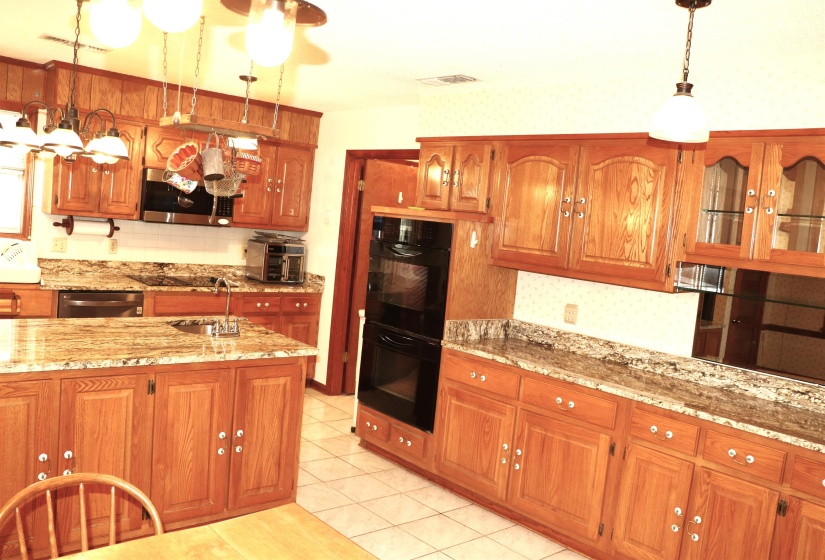 Kitchen featuring extensive wood cabinetry, stone countertops, and tile flooring