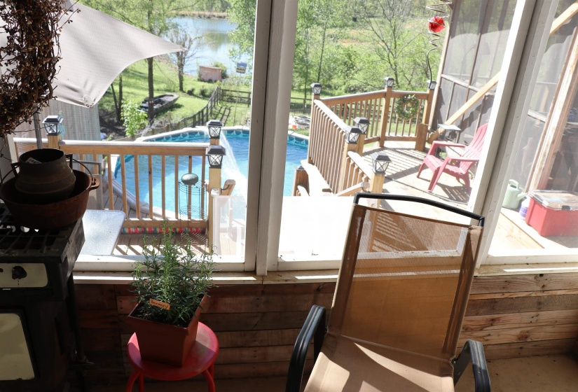 Wooden deck with an outdoor pool, a grill, a water view, and a patio
