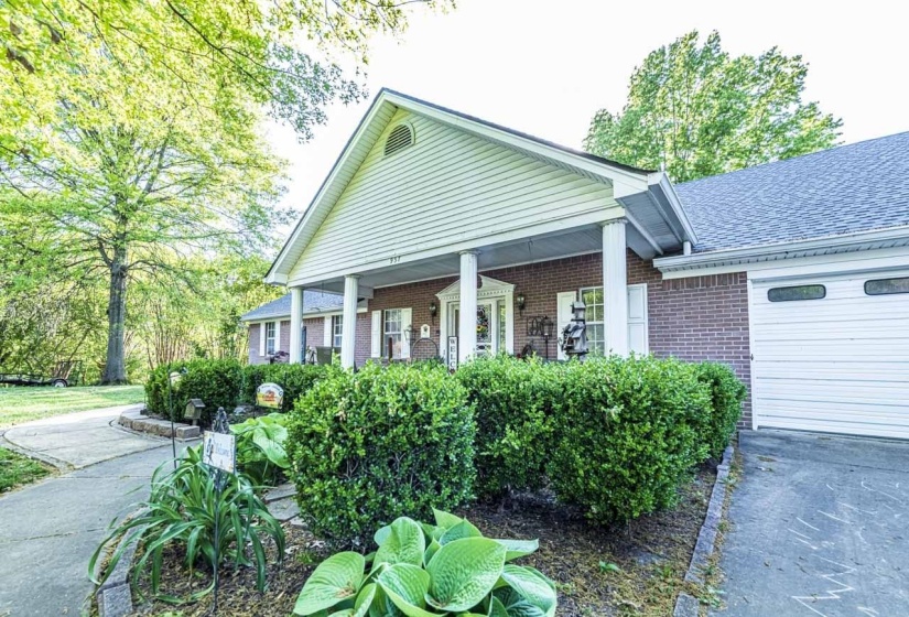 View of front facade featuring covered porch, brick siding, and a shingled roof