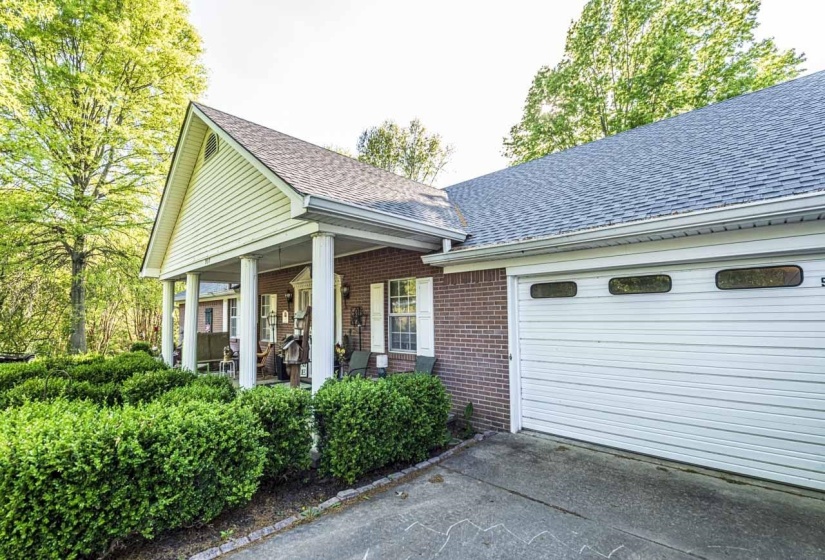View of front facade with roof with shingles, an attached garage, driveway, and brick siding