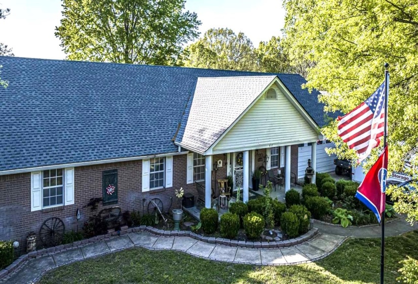 View of front of home featuring covered porch, a front yard, and brick siding