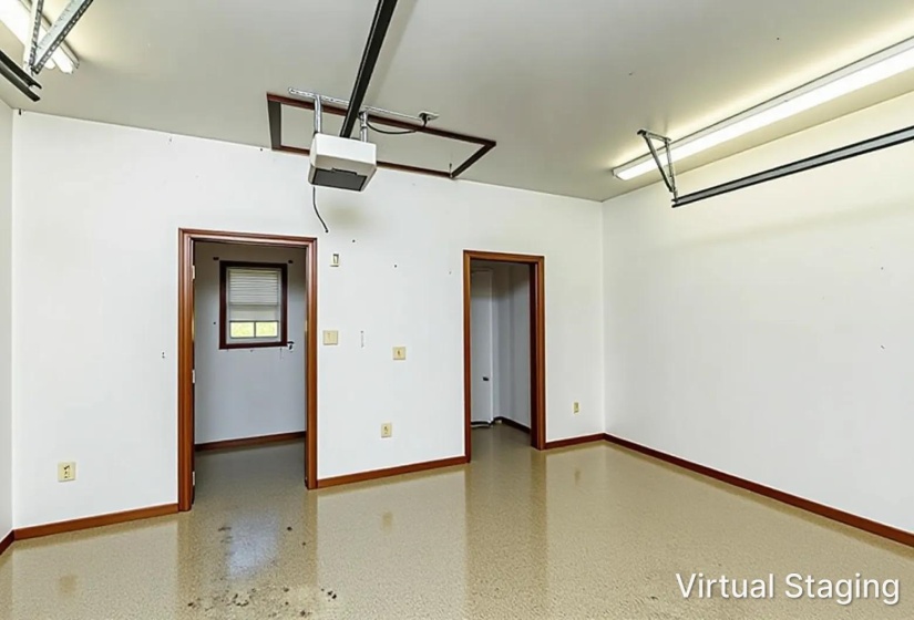 Spacious garage featuring a durable epoxy floor finish, two access doorways with wood trim, and bright overhead fluorescent lighting