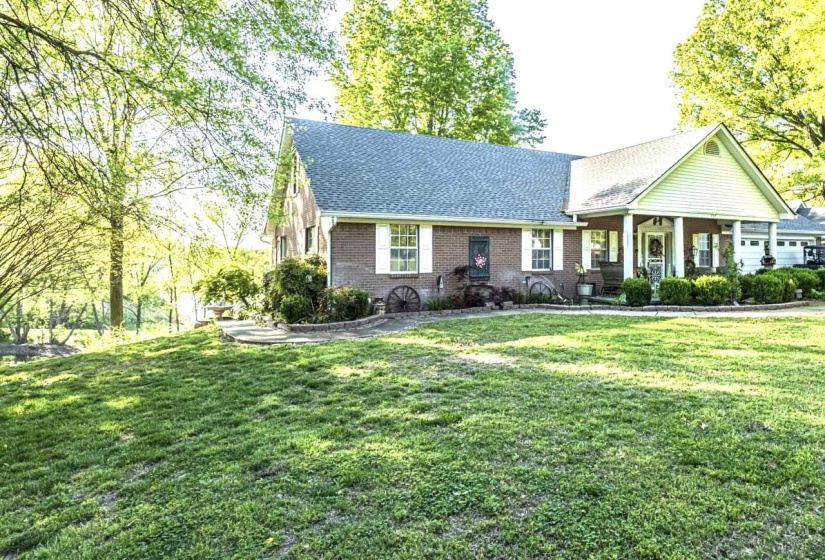 View of front of property featuring covered porch, a front yard, roof with shingles, and brick siding