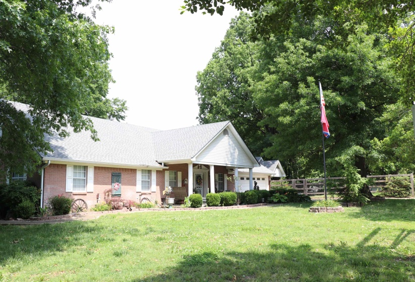 Brick facade home featuring a covered front porch, white window shutters, and an attached garage