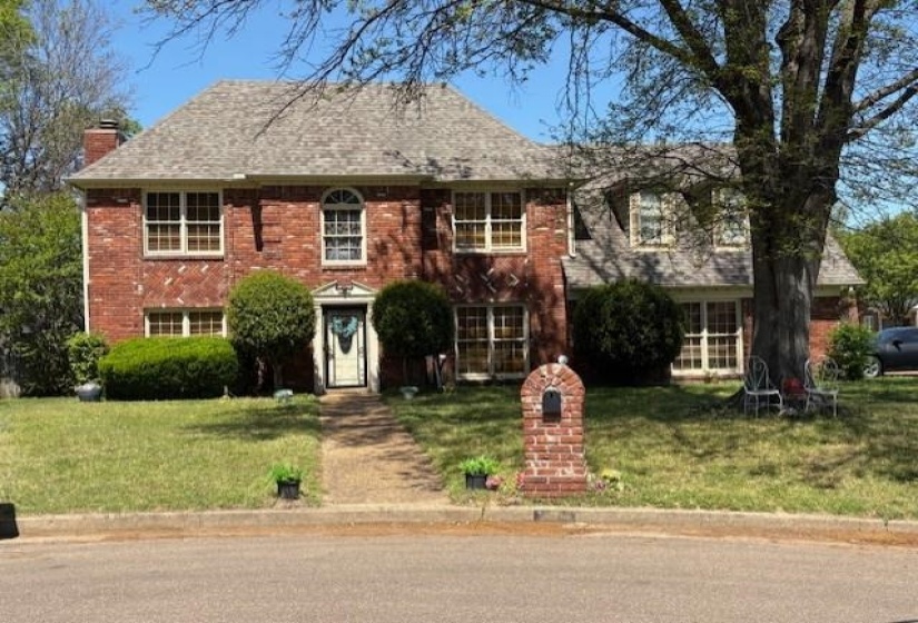View of front of house with a chimney, brick siding, and a front lawn