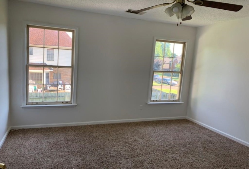Carpeted room with two double-hung windows, a ceiling fan with integrated lighting, and white baseboards
