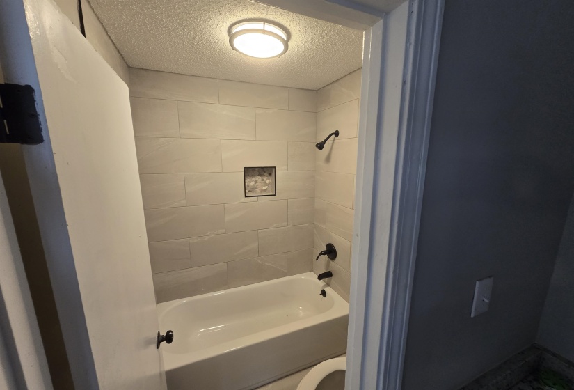 Bathroom featuring a textured ceiling and shower / tub combination