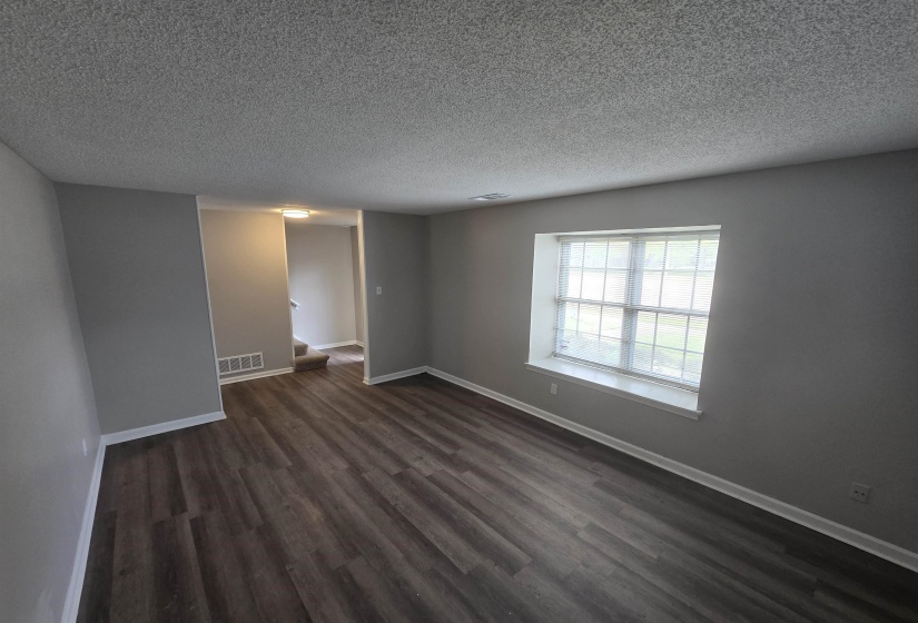 Spare room featuring dark wood-type flooring and a textured ceiling