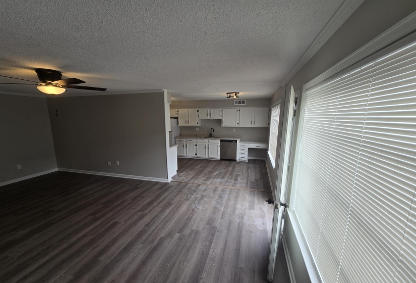 Unfurnished living room featuring dark wood-style floors, a textured ceiling, and a ceiling fan
