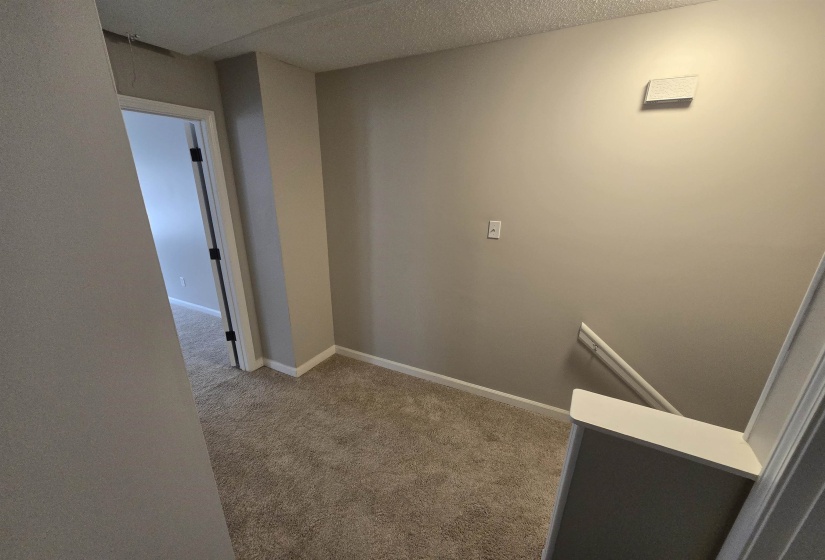 Corridor with light carpet and a textured ceiling