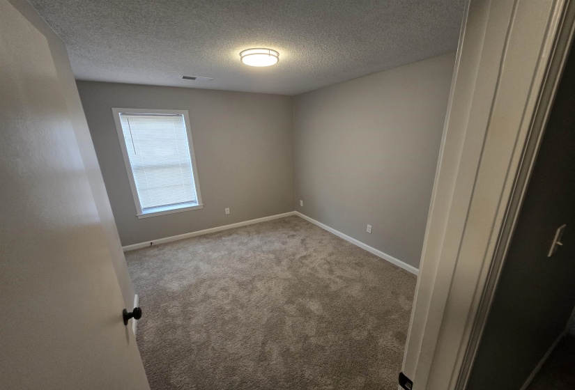 Unfurnished bedroom featuring a textured ceiling and light carpet
