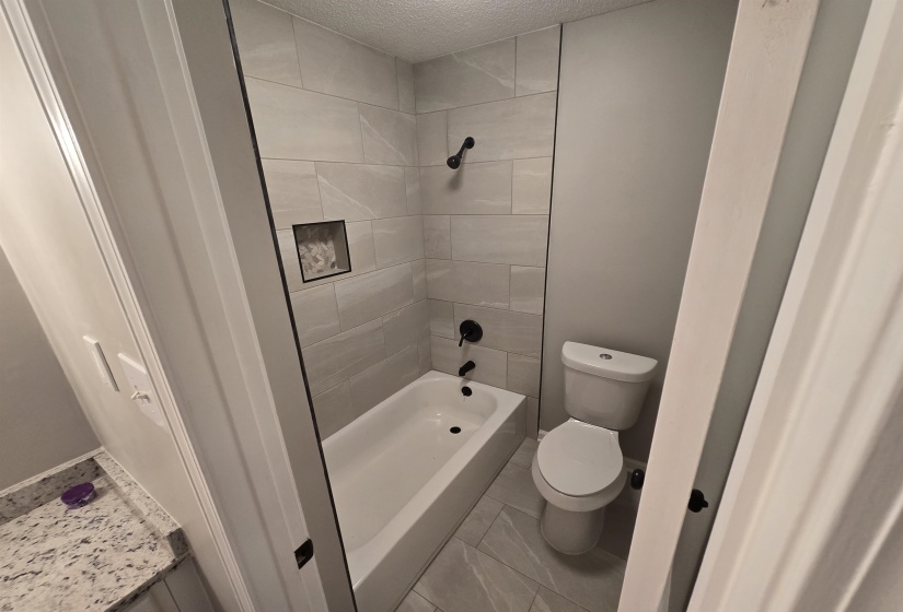 Bathroom featuring a textured ceiling, shower / tub combination, and vanity
