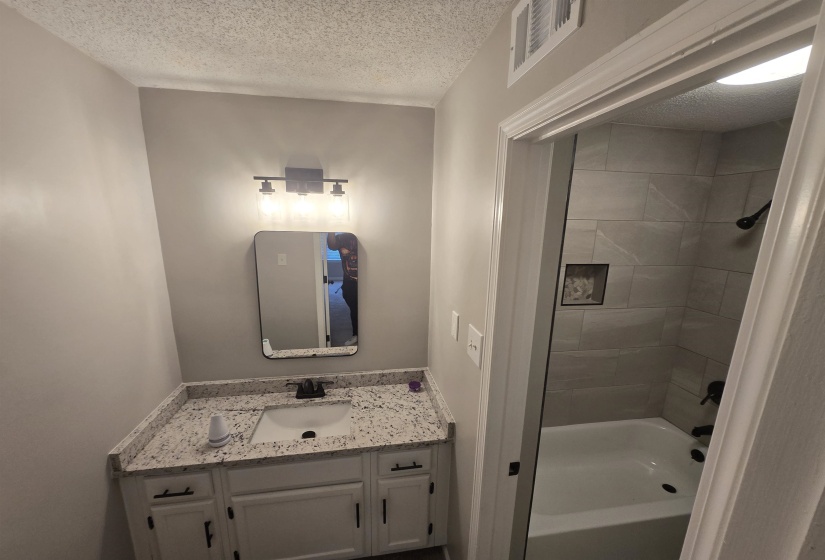 Bathroom with vanity, a textured ceiling, and bathtub / shower combination