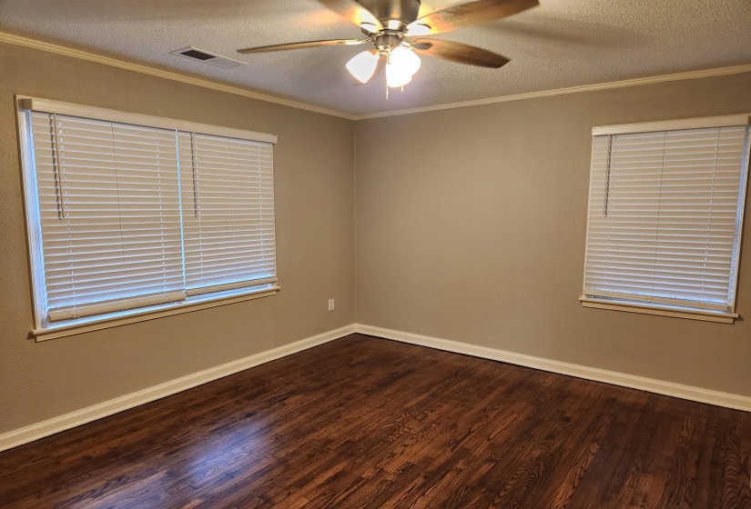 Spare room with crown molding, a textured ceiling, dark wood finished floors, and ceiling fan