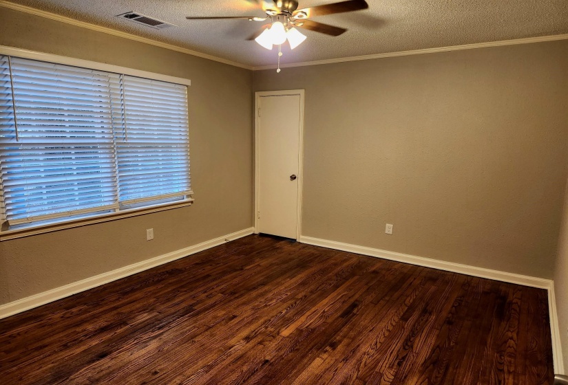Spare room featuring a textured ceiling, wood finished floors, ornamental molding, ceiling fan, and a textured wall