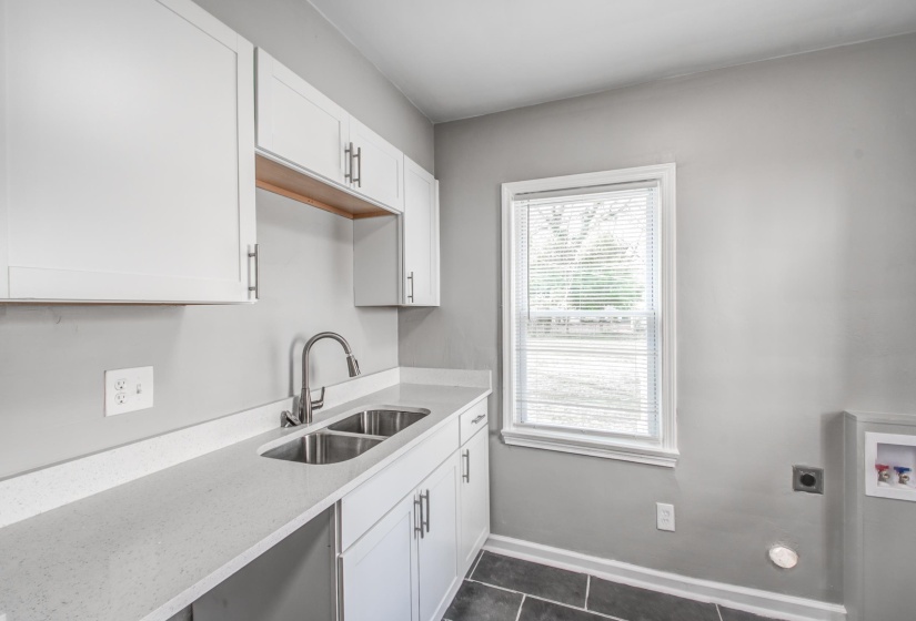 Kitchen with white cabinetry, light stone countertops, and dark tile patterned flooring