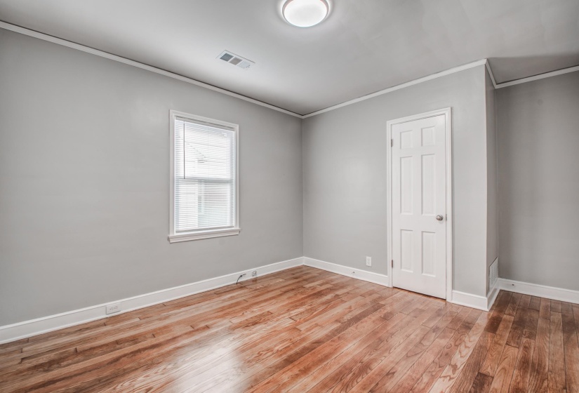 Unfurnished bedroom with ornamental molding and light wood-style flooring