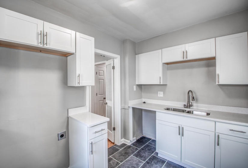 Kitchen with white cabinets, dark tile patterned floors, and light stone countertops