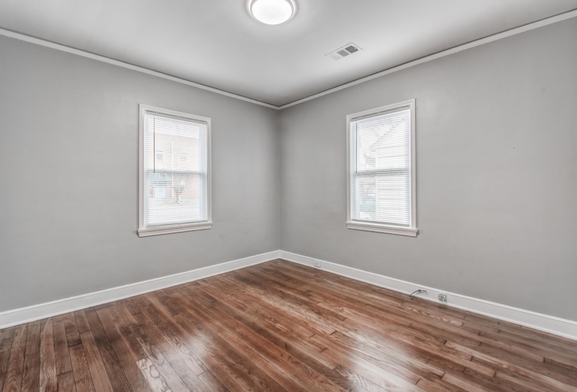 Empty room featuring ornamental molding and dark wood-type flooring