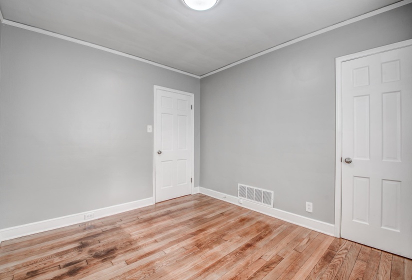 Empty room with ornamental molding and light wood-style floors