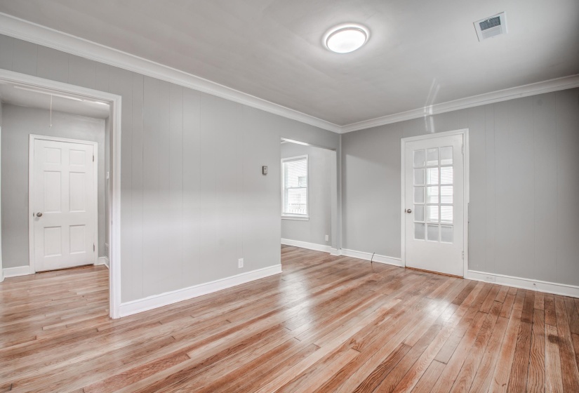 Empty room featuring ornamental molding, light wood-style flooring, and wooden walls