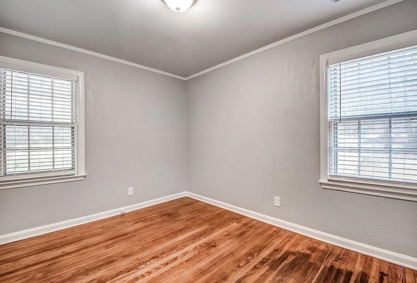 Unfurnished room with wood finished floors, healthy amount of natural light, crown molding, and a textured wall