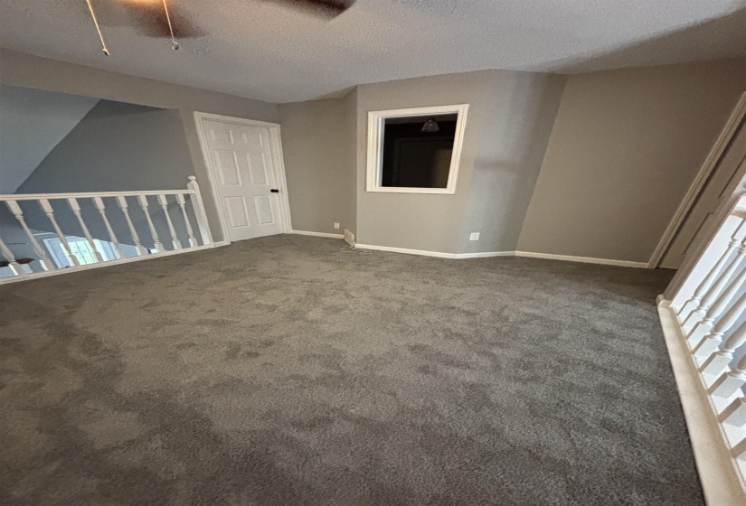 Empty room featuring a textured ceiling and dark colored carpet