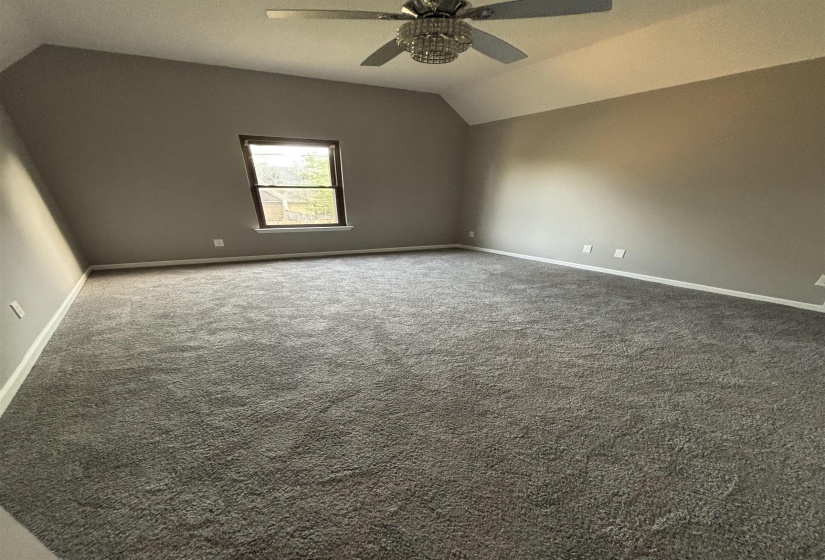 Spare room with vaulted ceiling, carpet floors, and ceiling fan