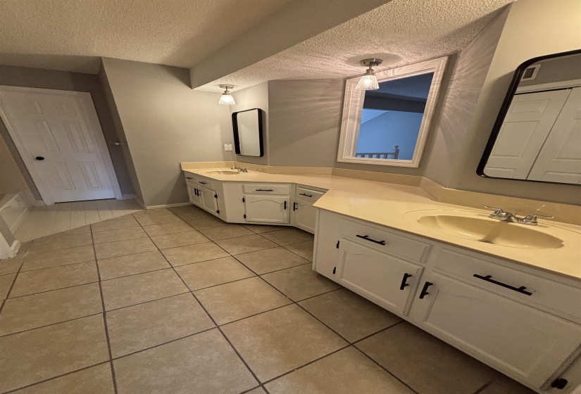 Full bathroom featuring double vanity, a textured ceiling, and light tile patterned flooring