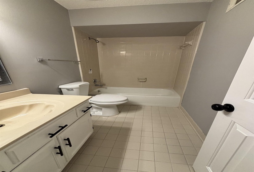 Full bathroom with vanity, shower / tub combination, light tile patterned floors, and a textured ceiling